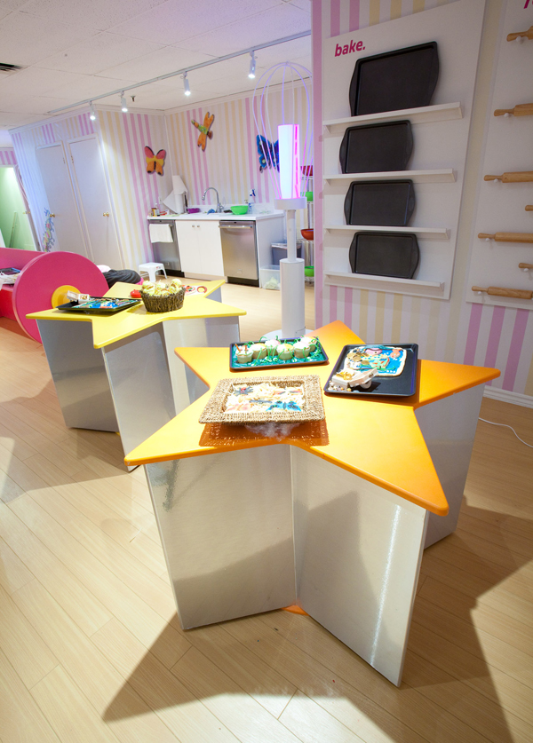 Tables shaped like star cookie cutters at the back of the bakeshop. Some of the finished recipes are visible on top.